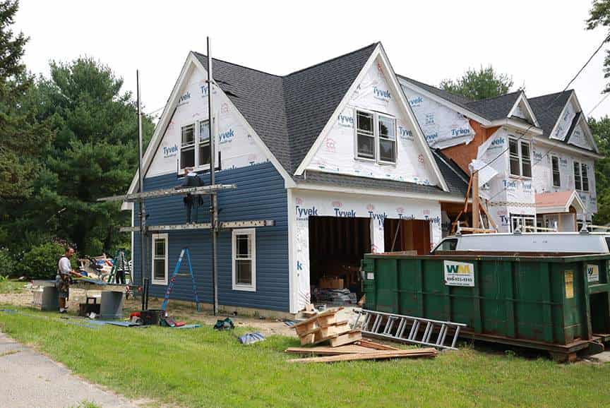 Garage addition with a loft under construction, scaffolding on the gable and a dumpster on site