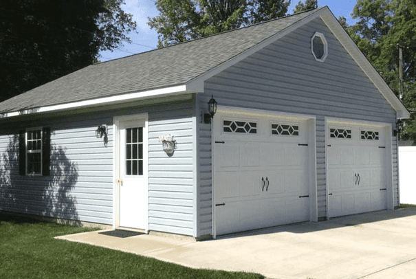 Two car detached garage with light blue siding, an oval gable window and a side entry door