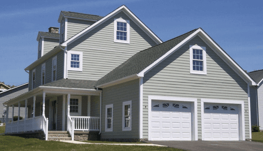 Two car garage addition in sage siding, attached to a two storey house with a front porch