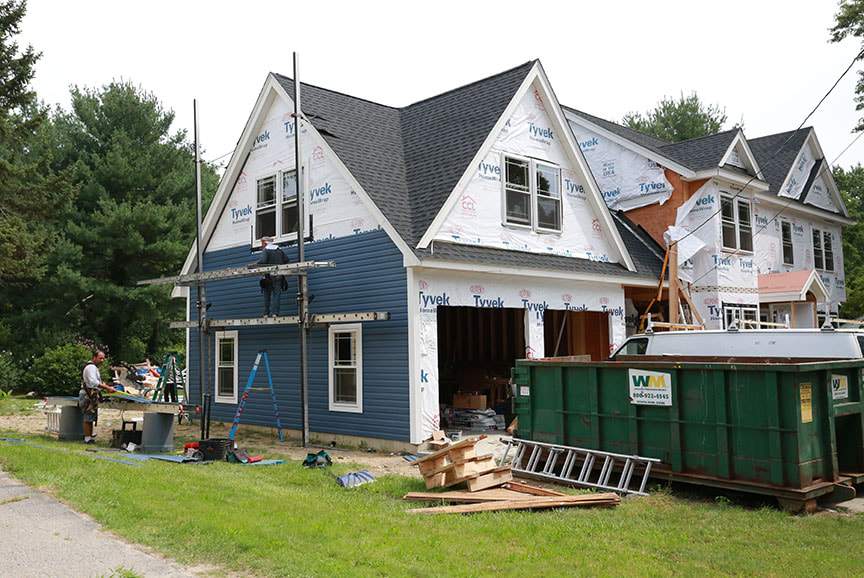 Garage addition with a loft under construction, scaffolding on the gable and a dumpster on site