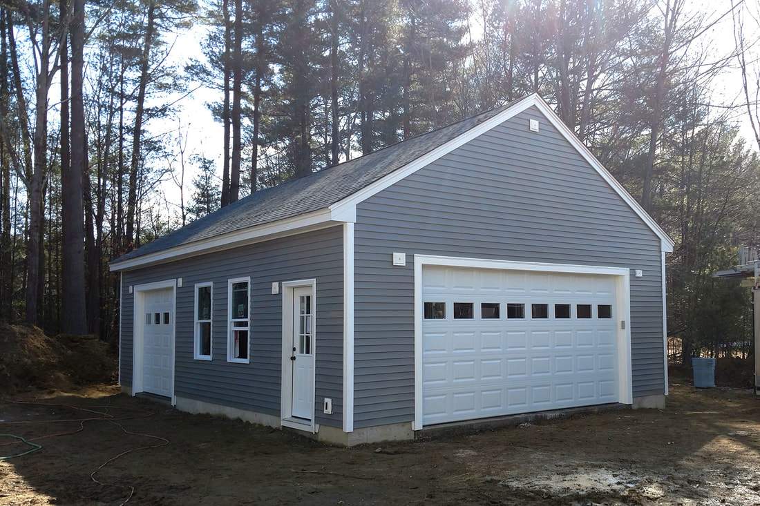 Grey detached garage with a double wide overhead door, plus a side entry door and single bay