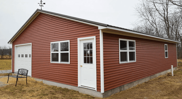 One car detached garage with red siding, a side entry door and a weathervane on the roof
