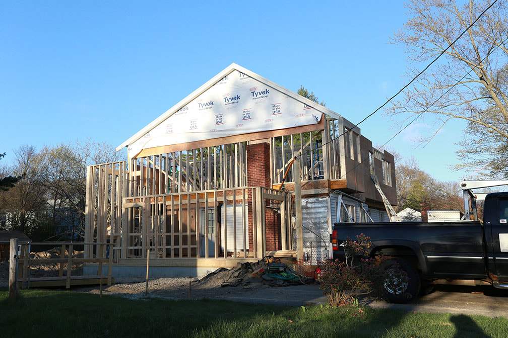 Two storey garage addition being framed onto a house, with housewrap on the new gable