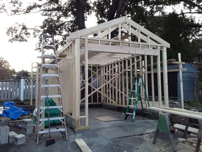 Single car garage being stick framed on its slab, with the roof structure going up